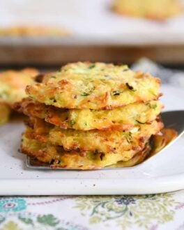 Cheesy baked zucchini bites stacked on a spatula.