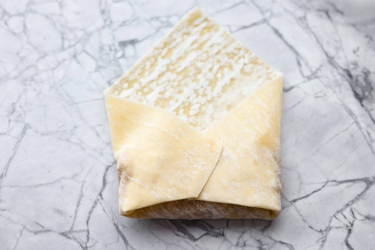 The egg roll being wrapped around the filling. 