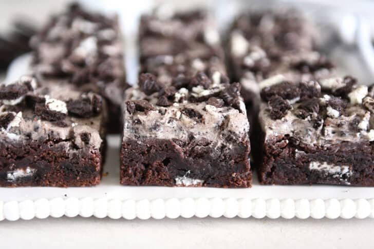 Three squares of Oreo frosted brownies on white tray.