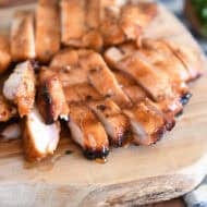 Wood tray with sliced pieces of grilled chicken.