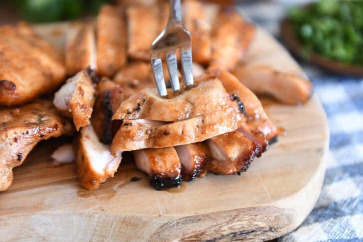 Wood tray with sliced pieces of grilled chicken.