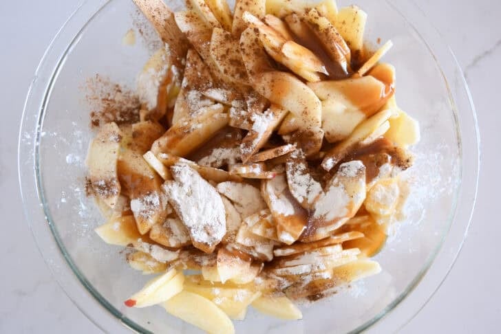 Glass bowl with sliced apples, caramel and flour.