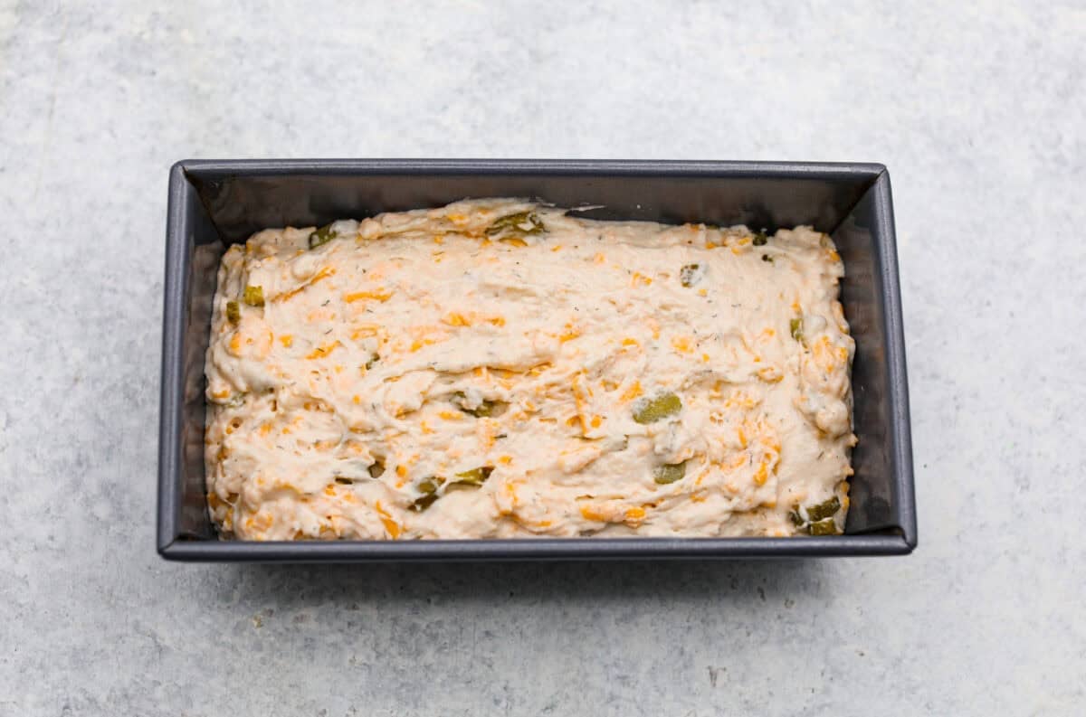 Dill pickle bread dough added to a loaf pan. 