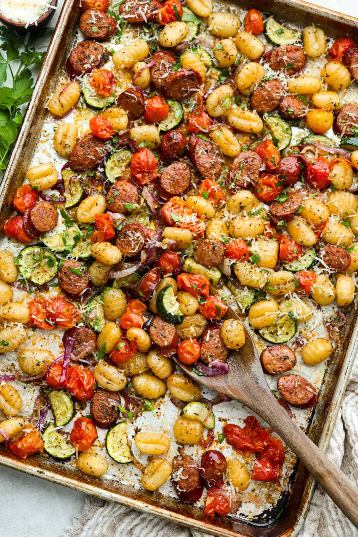 Sheet pan gnocchi cooked and toped with parmesan cheese and parsley. 