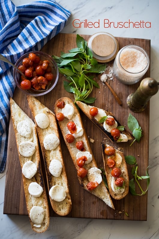Grilled Bruschetta Recipe with Mozzarella Cheese, basil and Tomatoes @whiteonrice Grilled Bruschetta Recipe with Mozzarella Cheese, basil and Tomatoes on a cutting board