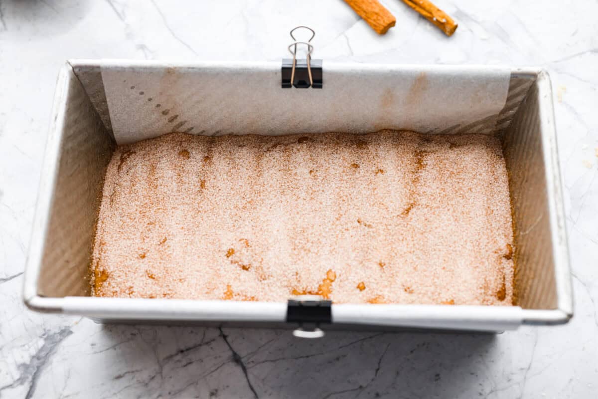 Half of the loaf batter added  to a loaf pan, then sprinkled with cinnamon and sugar. 