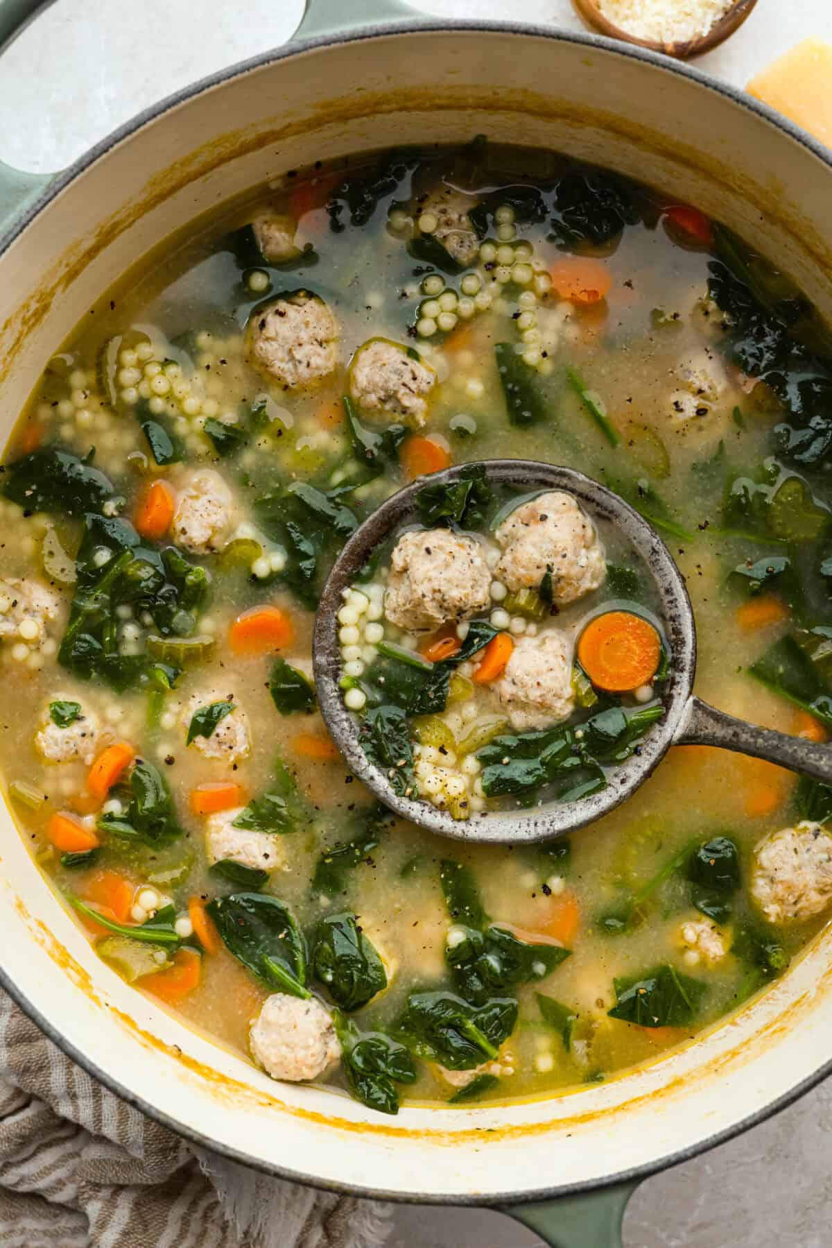 Large pot of Italian wedding soup, with a vintage ladle.