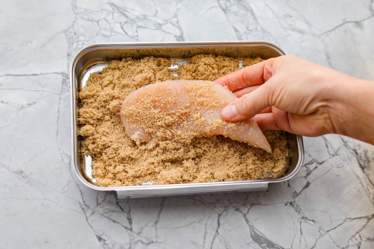 Chicken tenders being coated with the brown sugar mixture. 