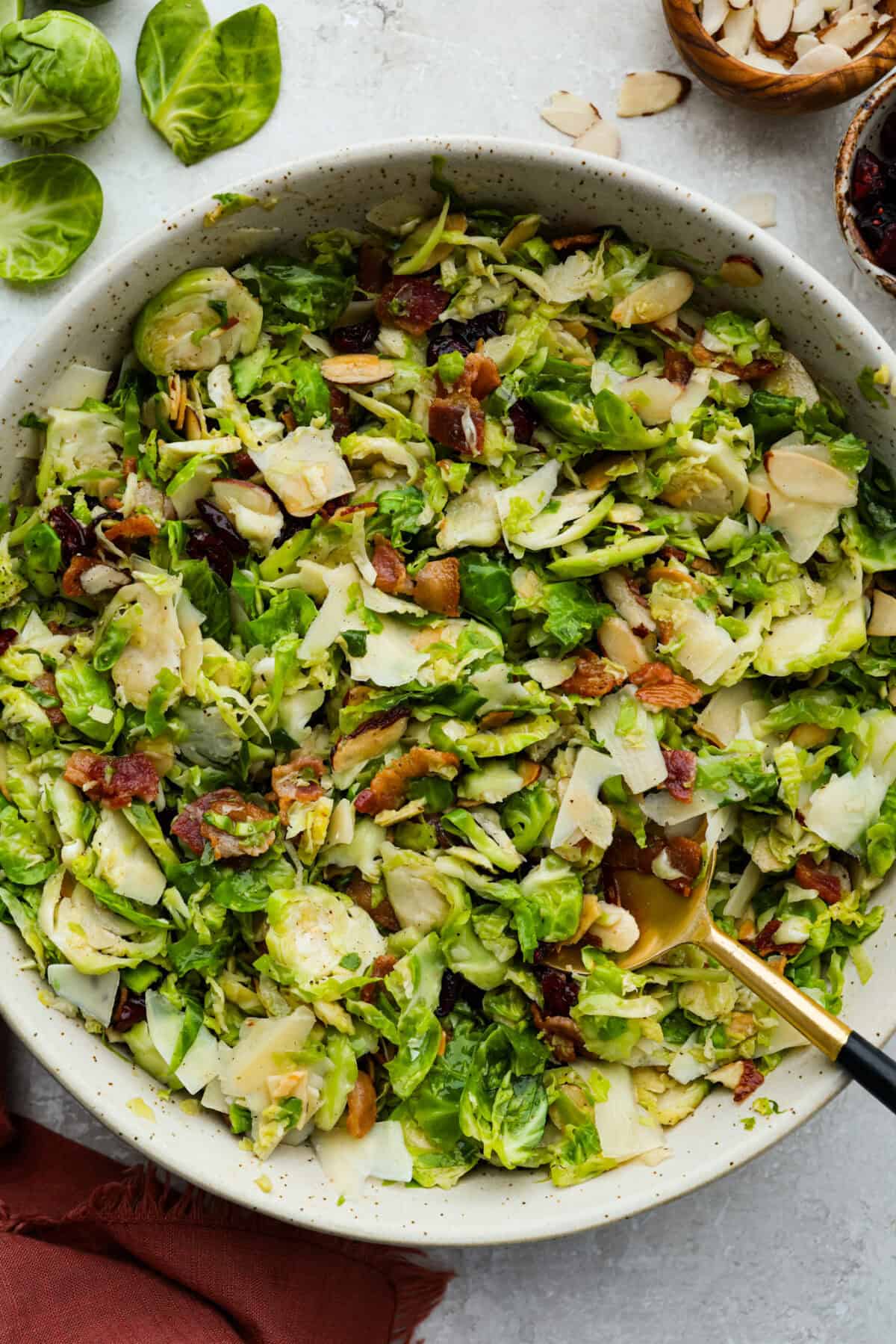 Large bowl of warm Brussels sprouts salad with bacon with a serving spoon. 