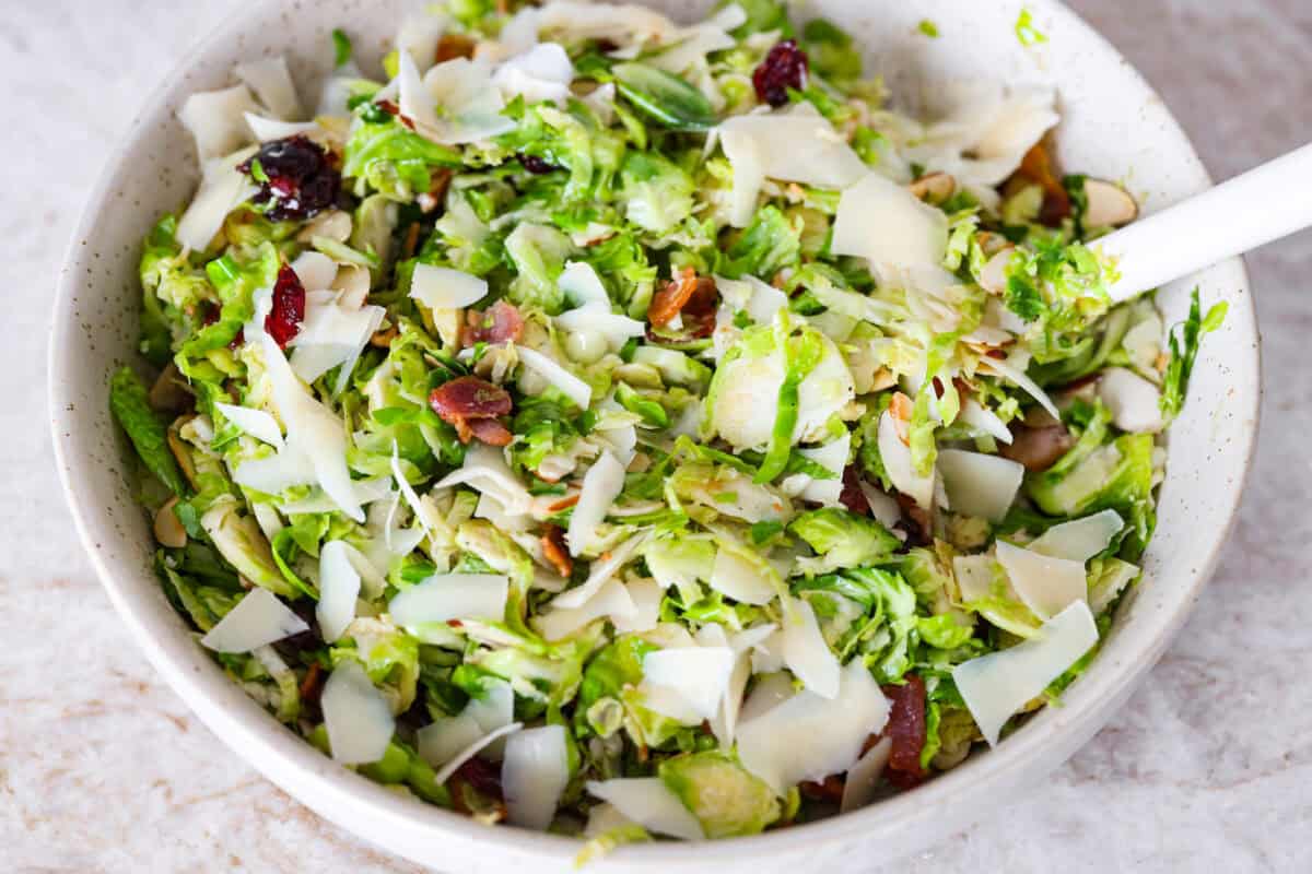 Dressing and parmesan cheese added to the warm Brussels sprouts salad with bacon and mixed together. 