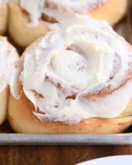 baked cinnamon rolls with frosting on sheet pan