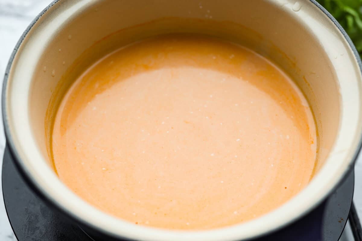 Sauce ingredients added to a saucepan and combined with coconut milk. 