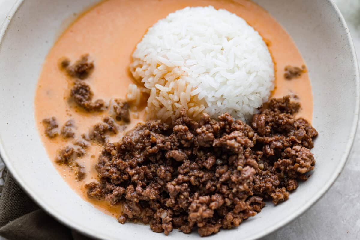 Beef and rice added to a bowl and surrounded in the coconut curry broth. 