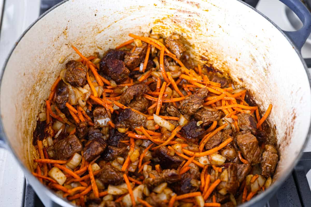Carrots, onions and seasonings aded to the dutch oven with the beef. 