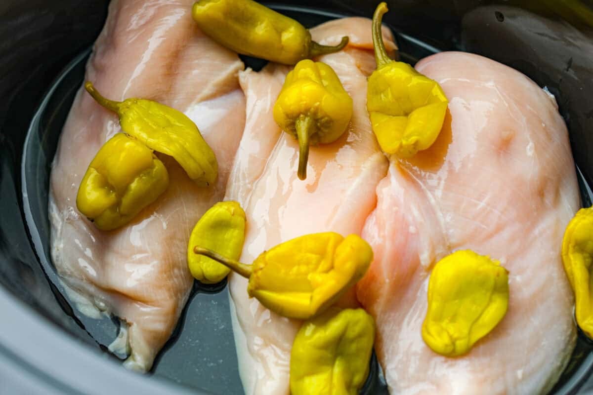 Chicken breasts and pepperoncini peppers and their brine in a slow cooker. 