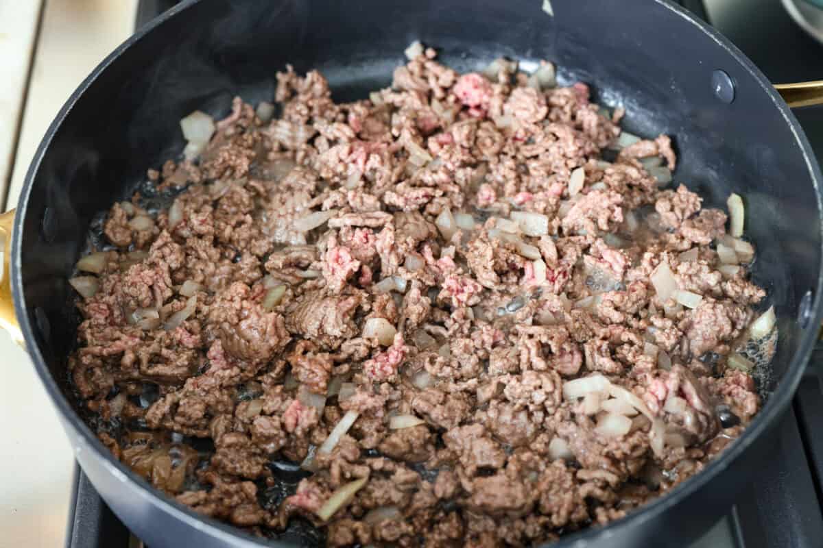 Ground beef and onions cooking in a skillet. 