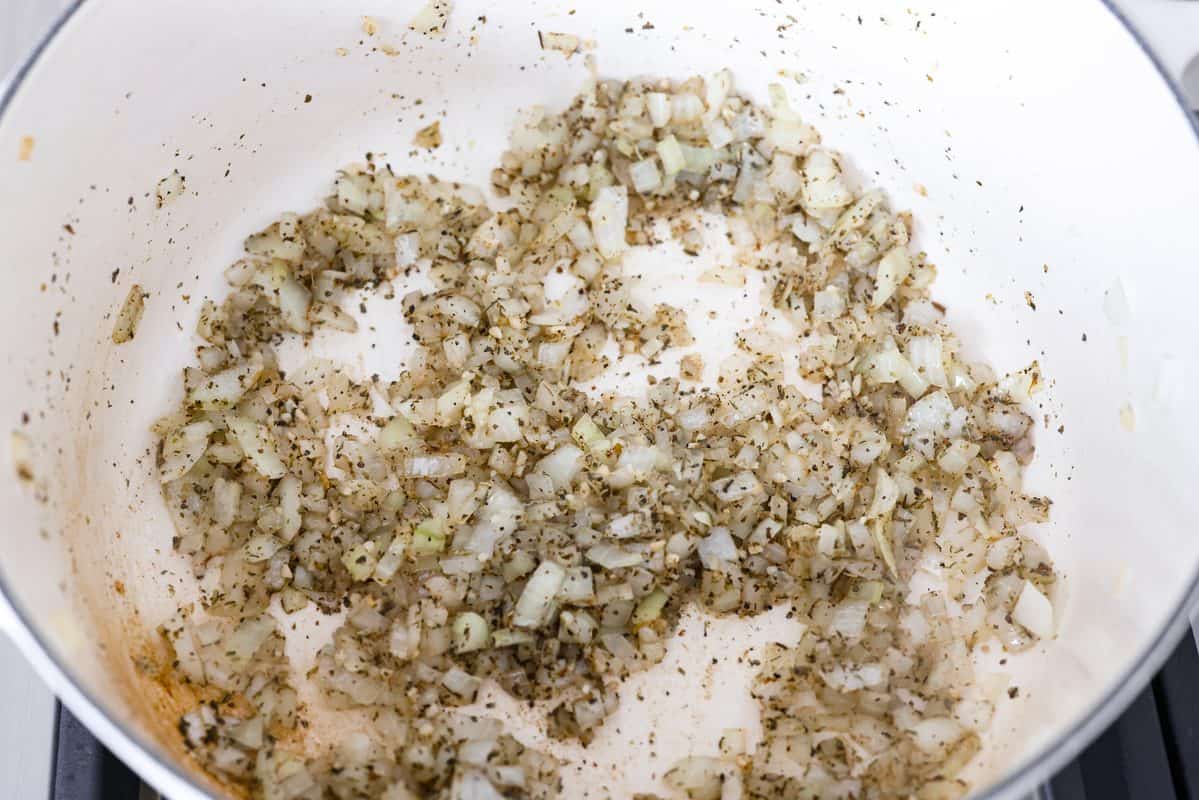 Onions, garlic, and seasonings cooking in olive oil a pot.