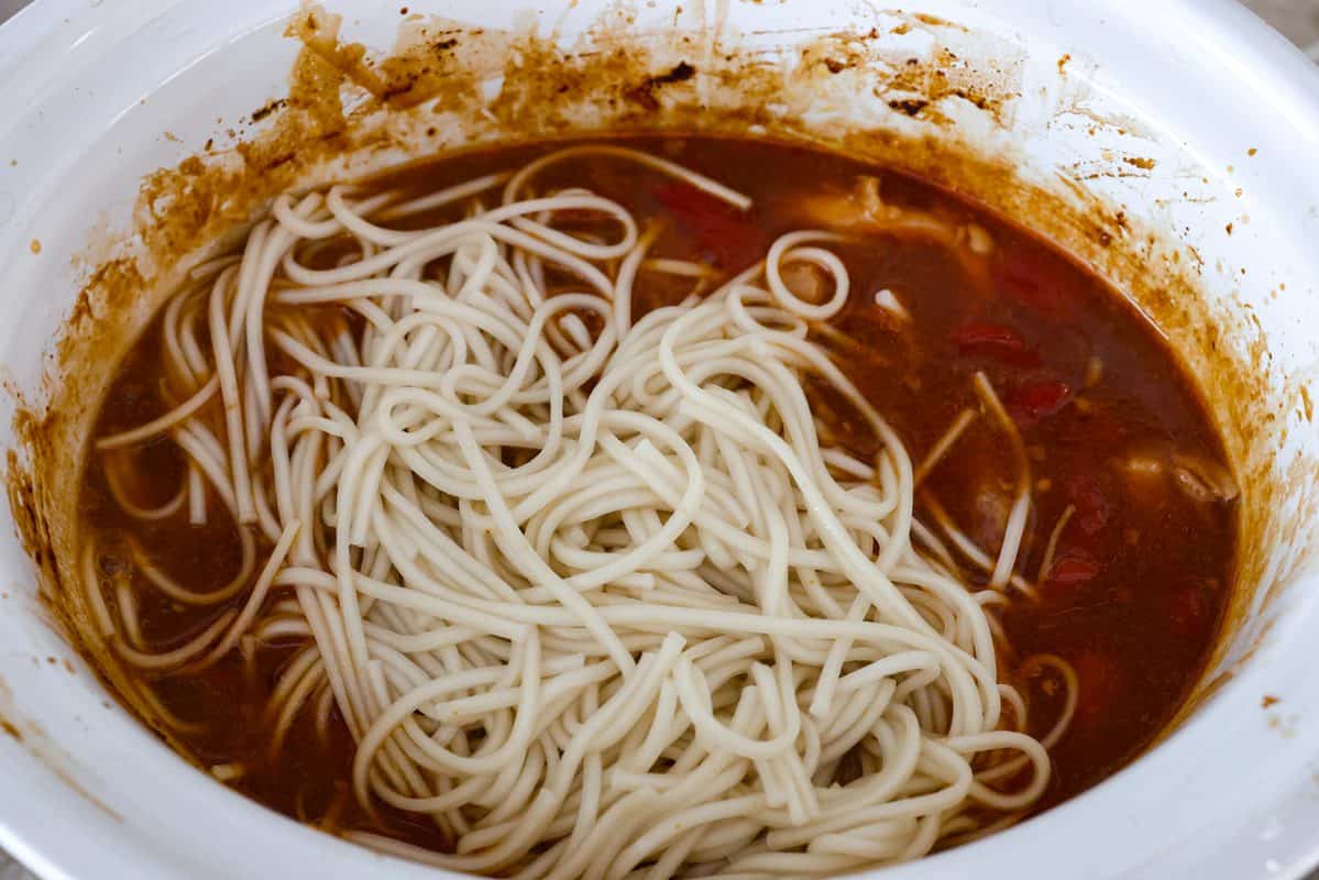 Cooked noodles added to the top of the cooked honey garlic chicken in the slow cooker. 