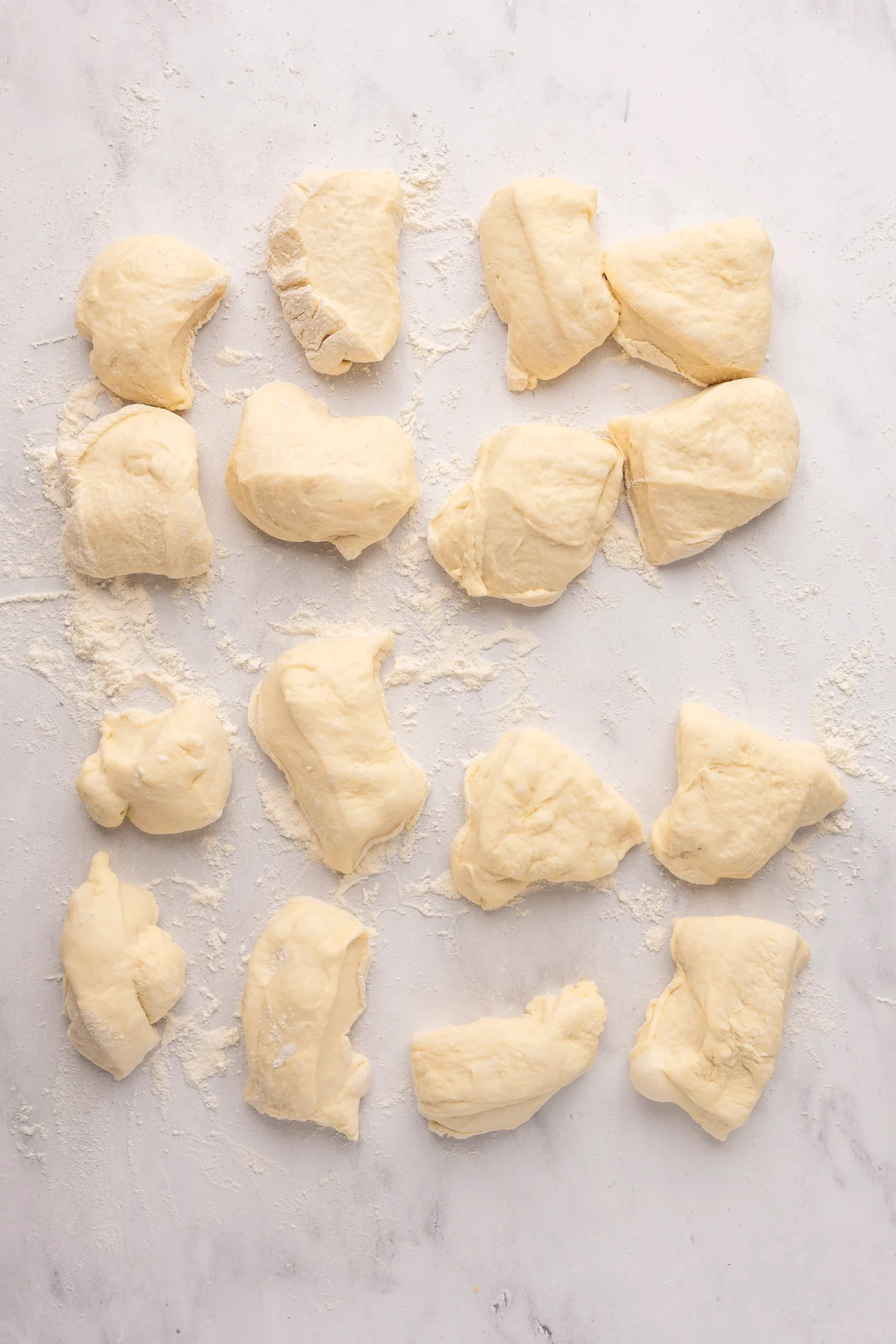 english muffin dough in 16 equal pieces on flour dusted surface
