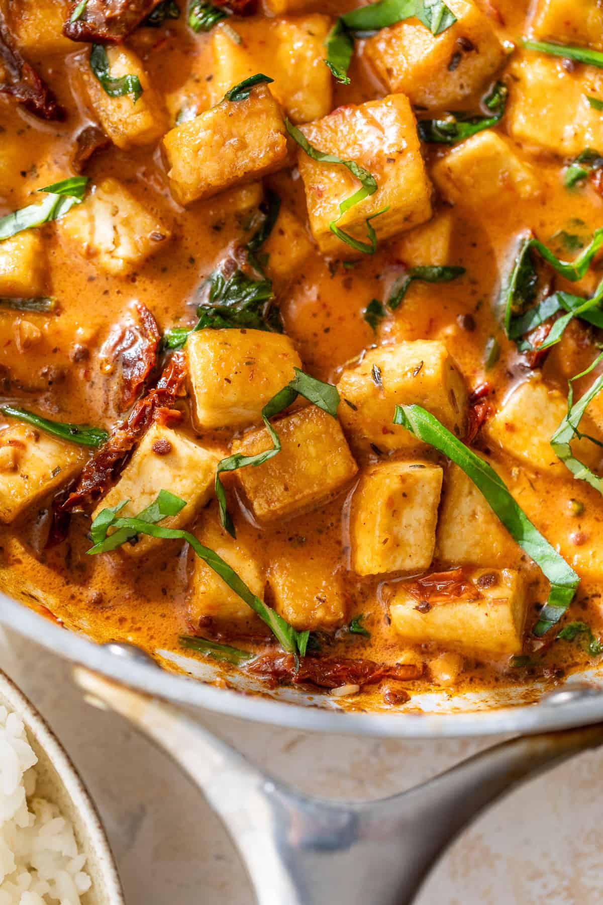 Marry me tofu in a creamy, orange-colored sauce with sun-dried tomatoes and fresh basil.